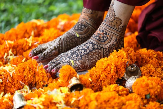 Beautiful mehndi-adorned feet surrounded by vibrant marigold flowers and ceremonial bells.